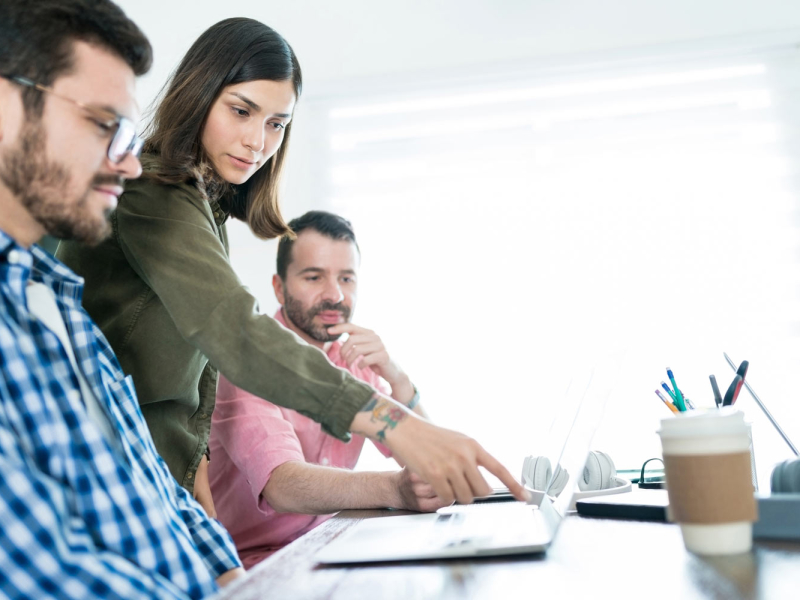 empresaria-explicando-sus-colegas-sobre-computadora-portatil-reunion-junta-lugar-trabajo