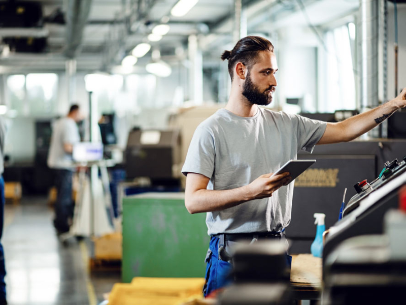 ingeniero-industrial-usando-panel-tactil-mientras-opera-maquina-cnc-fabrica